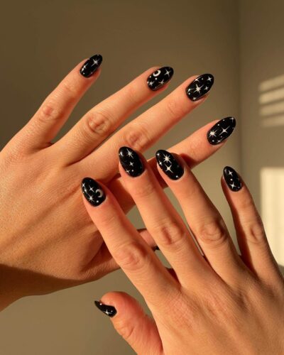 Black nails with a constellation of white stars and moons, offering a whimsical celestial theme.