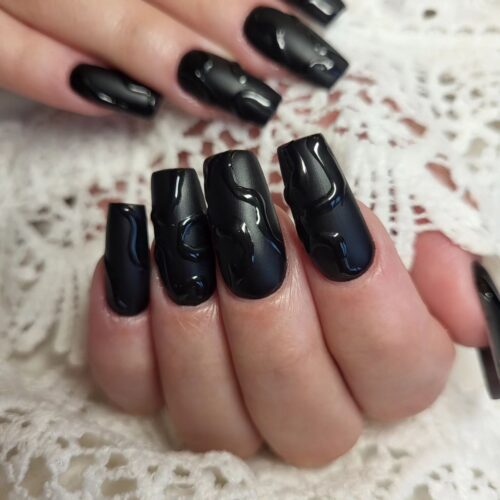 Black glossy nails with a liquid-like metallic sheen, giving a bold and futuristic look.