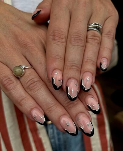 Black French manicure featuring silver constellations on a transparent base.