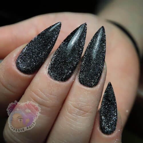 Close-up of hands with black nails showcasing a captivating cat-eye design with a metallic sheen.