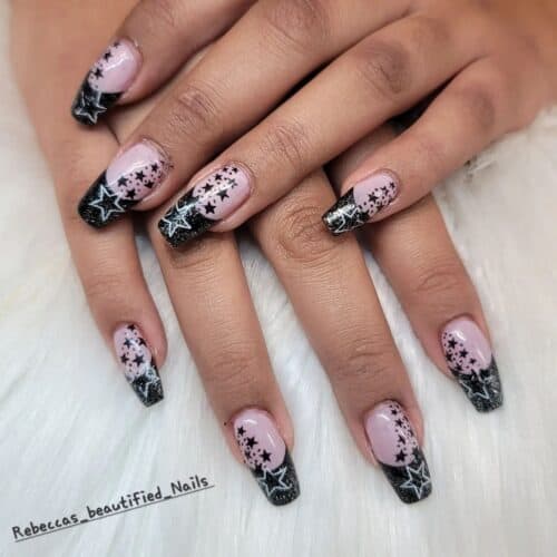 Coffin-shaped nails with black French tips and starry patterns.