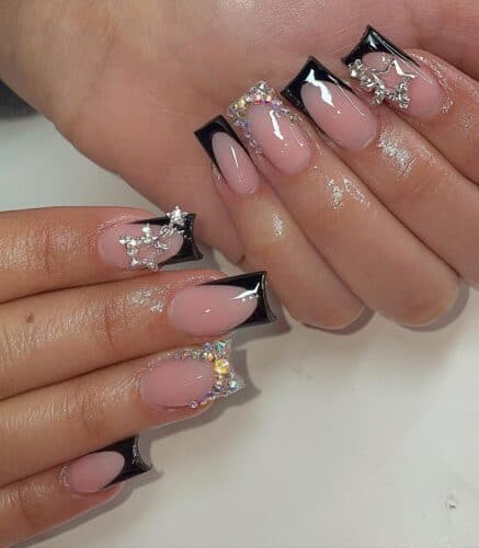 Square-shaped nails with glossy black French tips embellished with rhinestones and star accents.