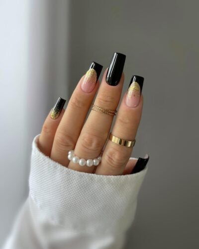 Nails featuring a combination of glossy black, soft pink, and gold glitter accents for a luxurious and glamorous look.