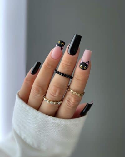 Pink nails with cute black cat faces and alternating solid black nails, showcasing a playful yet chic style.