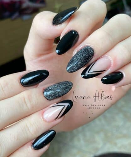 Glossy black nails with a mix of solid, glittery, and geometric line designs, perfect for a modern and stylish look.