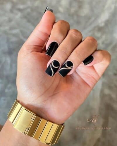 Long, square black nails with intricate gold spiral accents, offering a luxurious and elegant appearance.