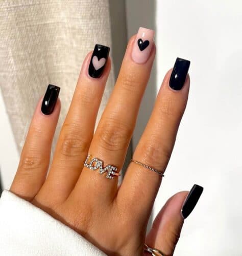 Hands with black and pink nails and small heart accents in black and pink.