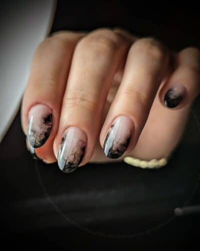 Elegant hands showing off nails with a black and white marbled design, providing a chic and artistic look.
