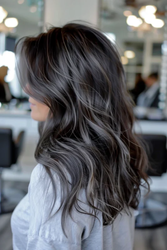 A profile shot of dark brown hair highlighted with ashy tones.