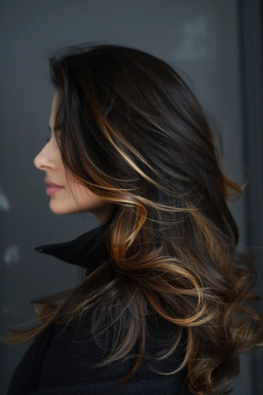 Cascading dark brown hair with subtle golden highlights that catch the light.