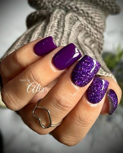 Alternating deep purple glossy and glittery textured nails against a soft grey background.