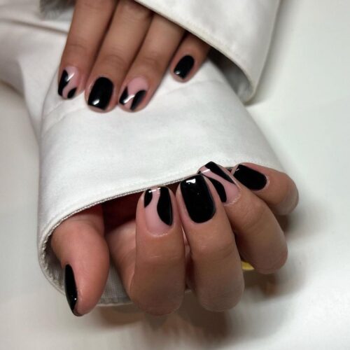 Black nails with sleek white swirl designs, portraying a minimalist yet elegant style.