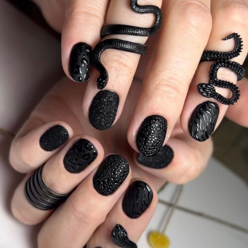 A variety of black nails featuring different textures and finishes, including matte, glossy, and raised patterns.