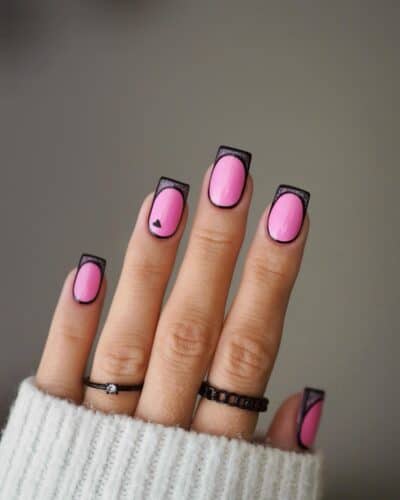 Square nails with a vibrant pink base and precise black French tips, accented by a single black heart detail.