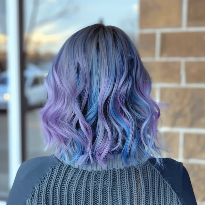 Woman with wavy hair colored in a blend of purple and blue shades.