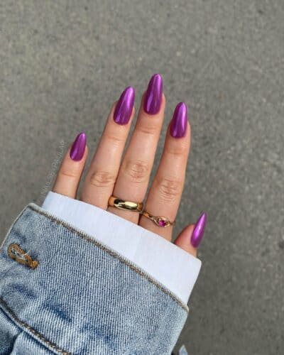 Almond-shaped nails with a glossy purple chrome finish on a denim jacket backdrop.
