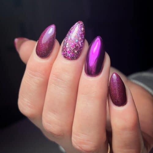 Almond-shaped nails painted in a shiny magenta gel polish against a crisp white cuff.