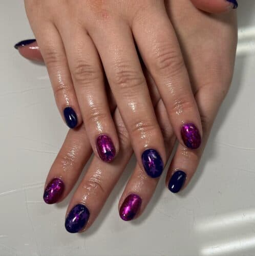 Oval-shaped nails painted in a glossy purple color, exemplifying classic elegance.