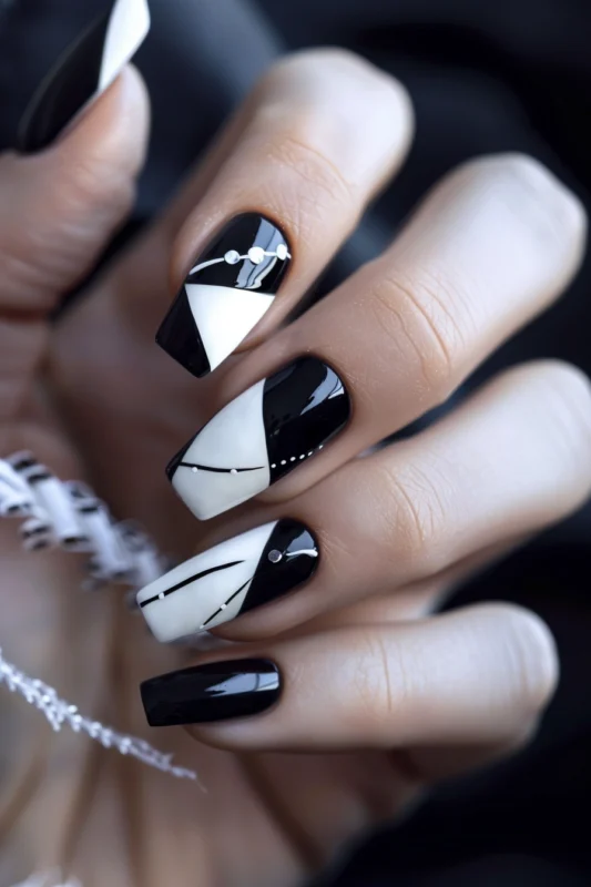 Geometric black and white coffin nails with rhinestone accents.