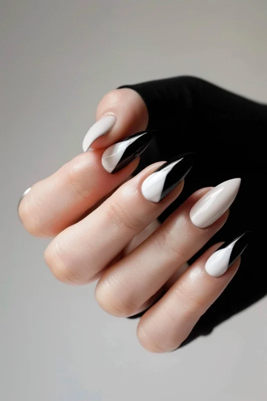 Alternating black and white French tips on almond-shaped nails.