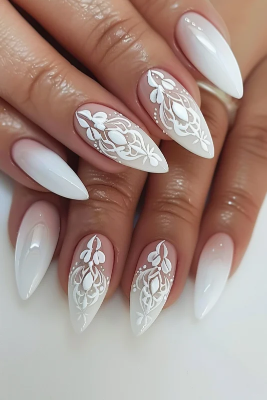 Almond-shaped nails with white lace-like floral detailing.