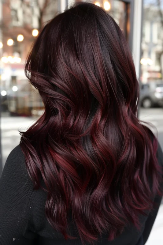 A person with lush dark red hair, styled with elegant waves.