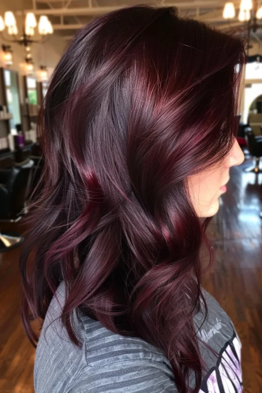 A person's hair in a deep red-brown color, with natural waves.