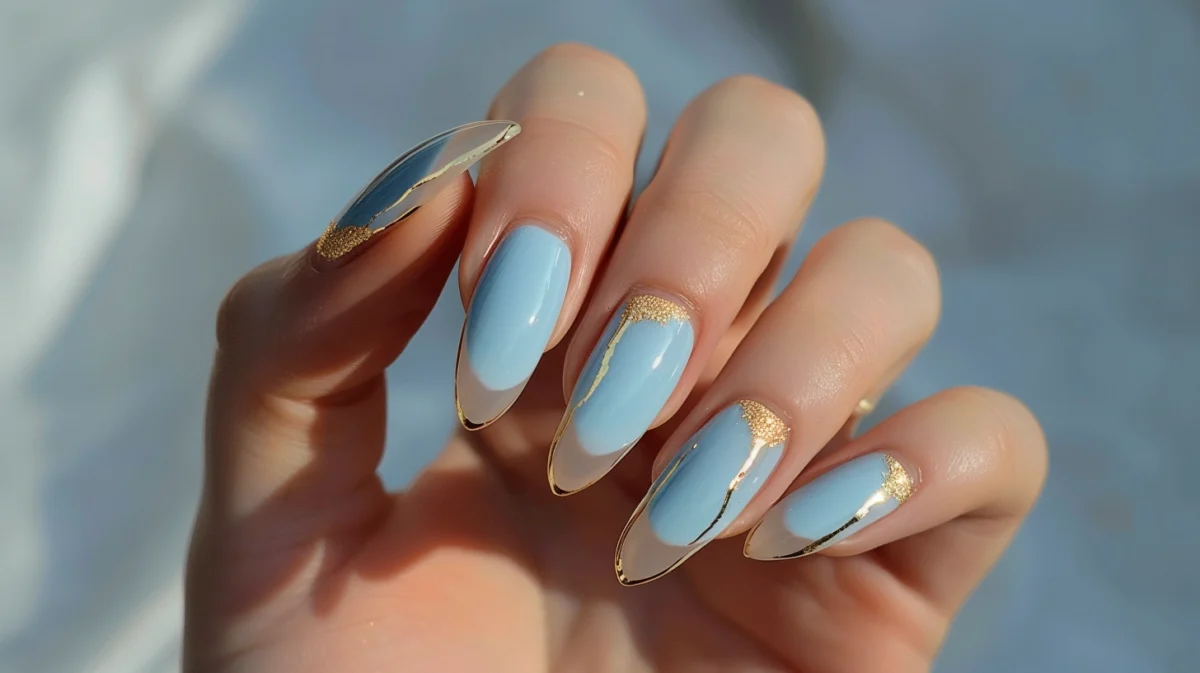 A hand with elegant fingers showing off light blue and gold French manicure.