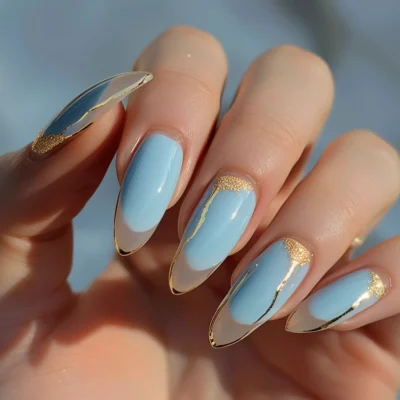 A hand with elegant fingers showing off light blue and gold French manicure.