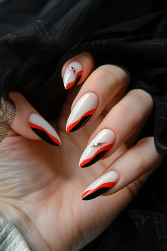 Artistic French tip nails with red and black waves and crystal accents.