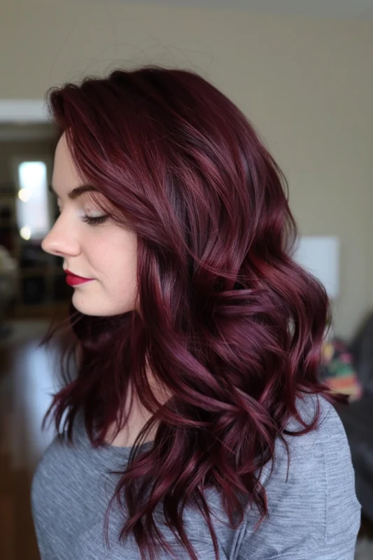 A woman with glossy, wavy maroon hair.