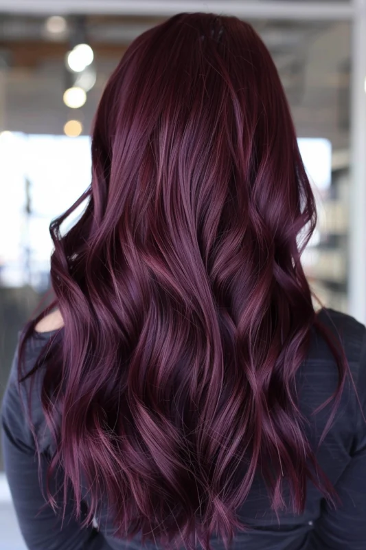A woman's hair with a deep merlot red color, styled in waves.