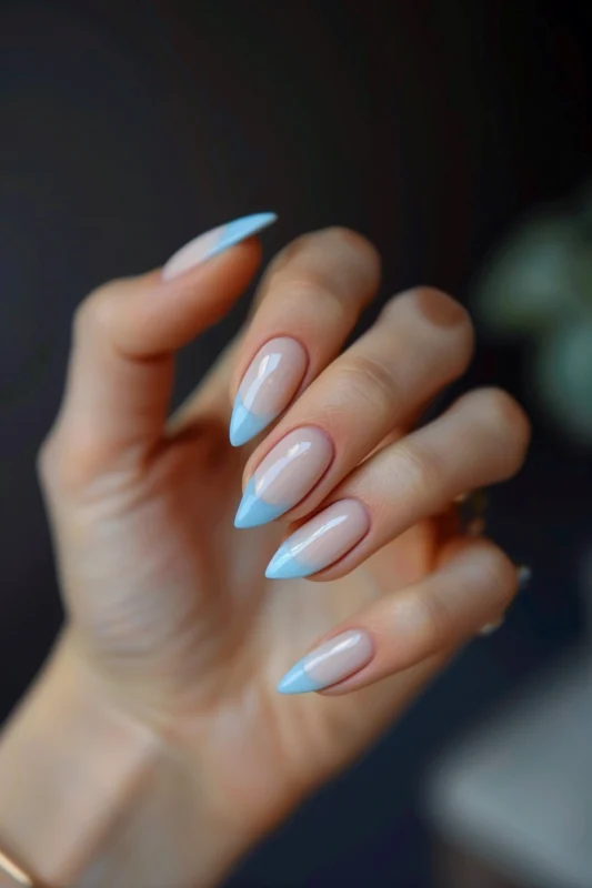 Pastel blue French tips on almond-shaped nails.