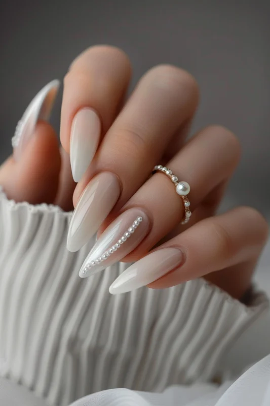 Stiletto pearl white nails with pearl accents.