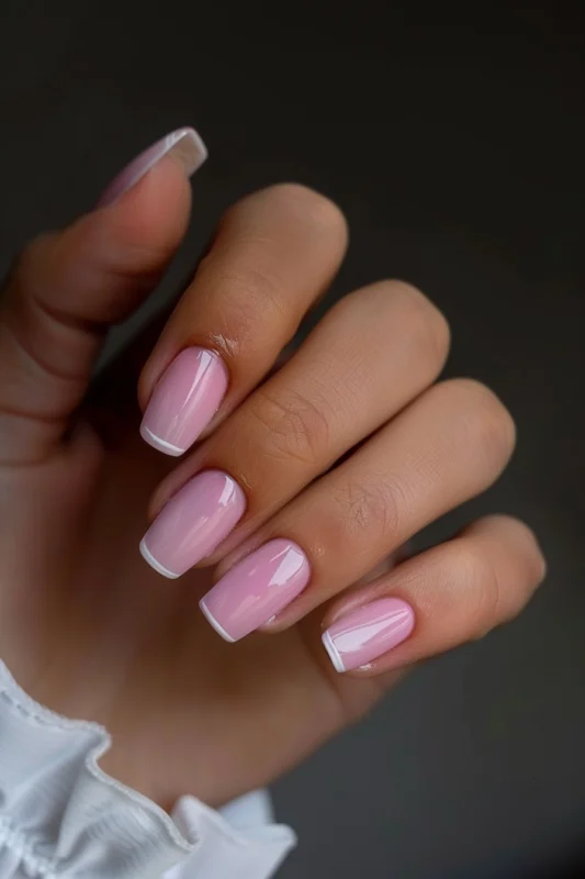 Short pink nails with subtle white French tips.