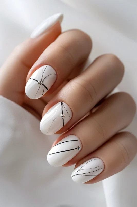 Short white rounded nails with minimalistic black accent lines.