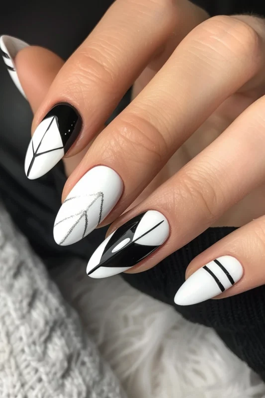 Simple white nails with abstract black art and glitter detail.