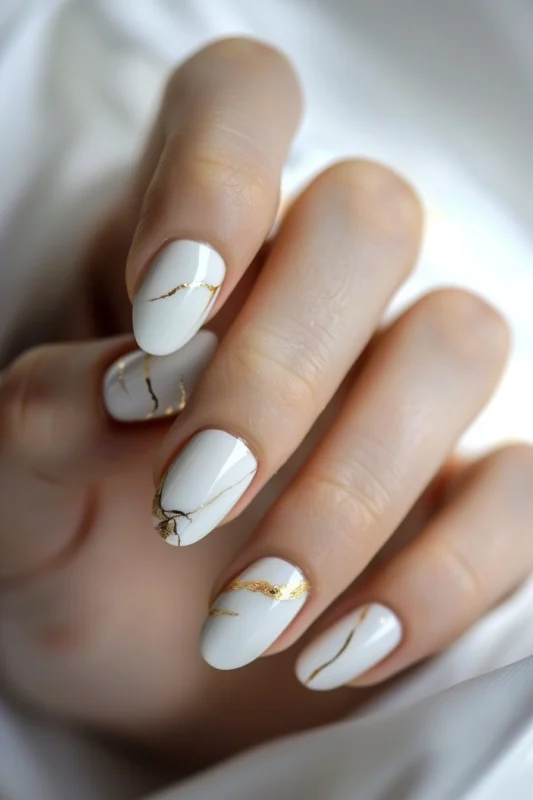 White short rounded nails with gold foil crack detail.