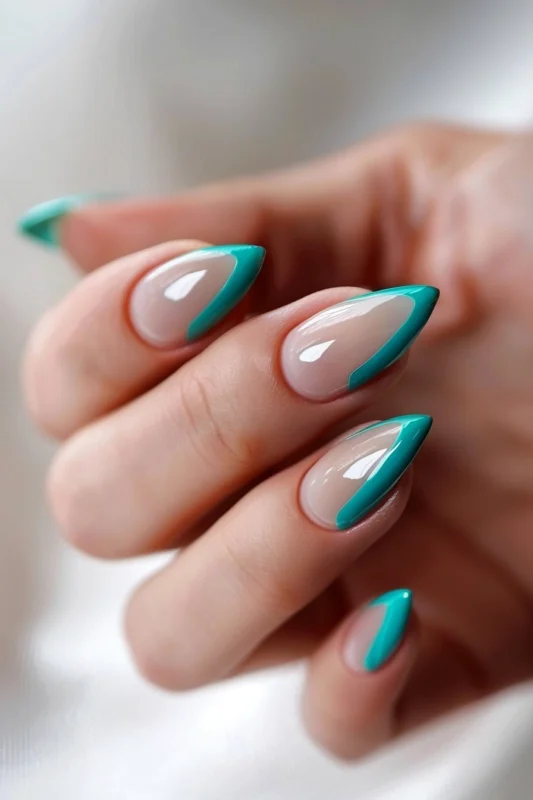 Teal French tips on almond-shaped nails.