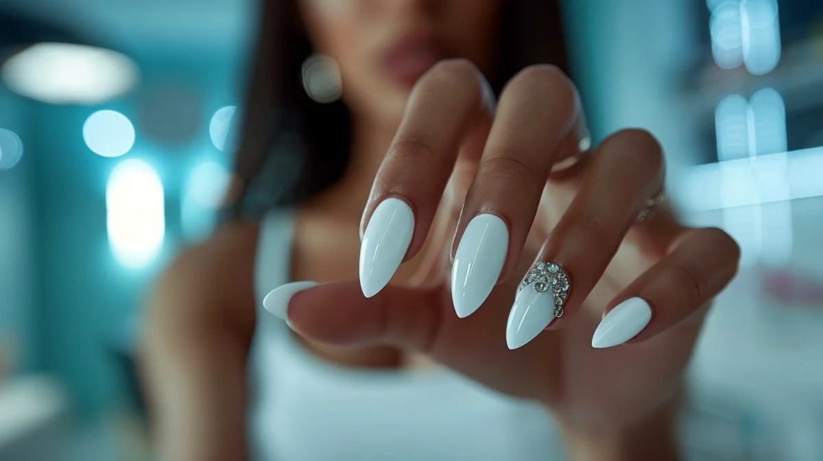 Woman showing off white nails with rhinestones detail.