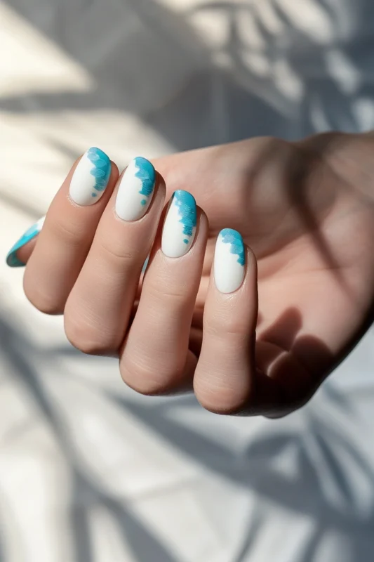 Short nails with a turquoise splash on a white base.