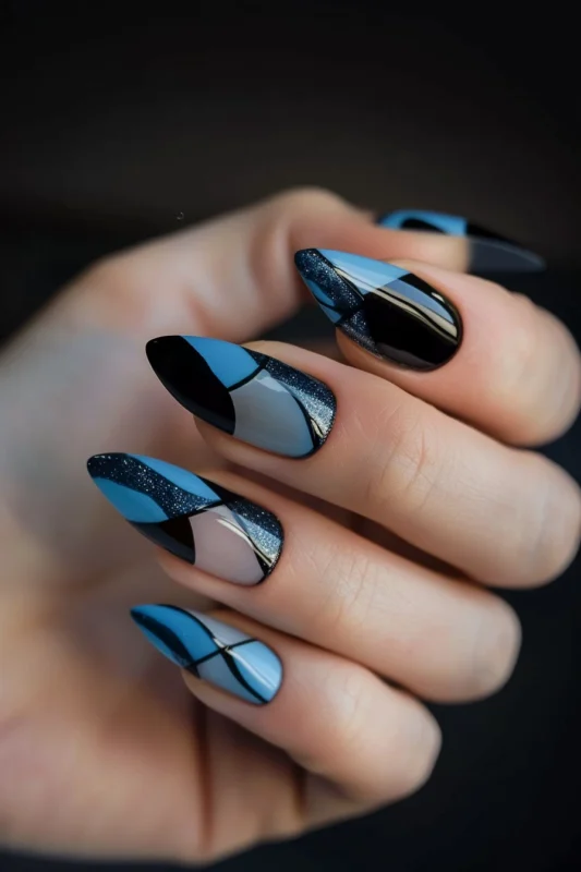 Blue and black nails with matte, glossy, and glitter textures in geometric designs.