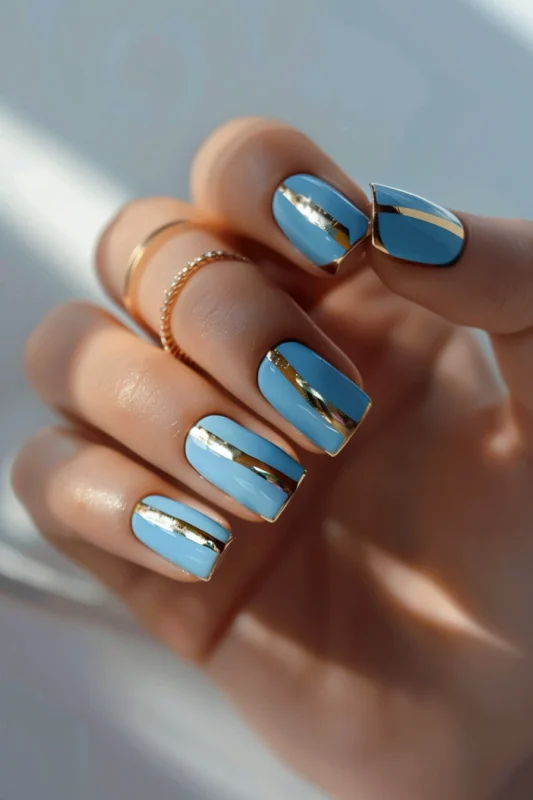 Short powder blue rectangular nails with gold foil accents.
