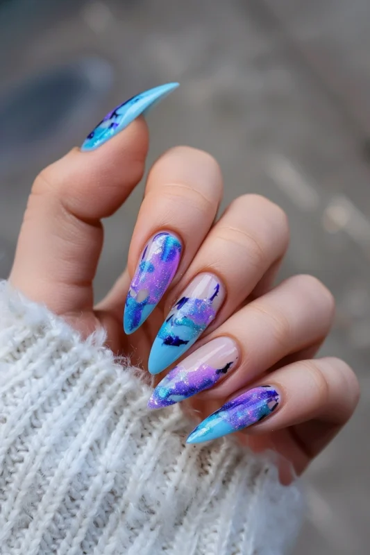 Stiletto nails with a blue and purple nebula design.