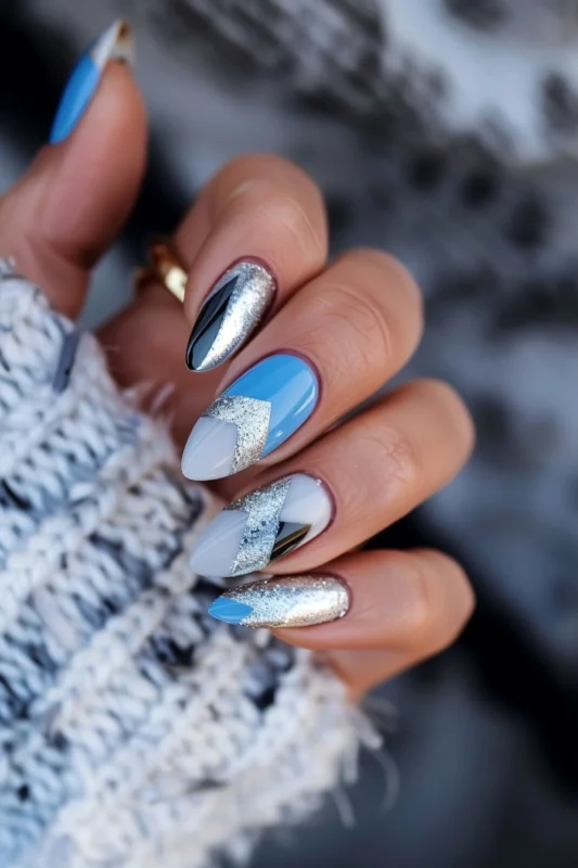Almond nails with blue, white, black, and silver geometric designs.