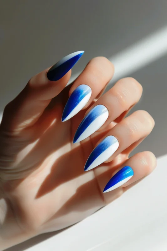 Stiletto nails with a blue and white gradient on a white base and glitter.