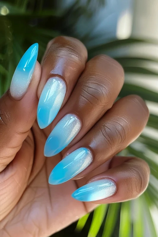 Stiletto nails with blue and white ombre and glitter.