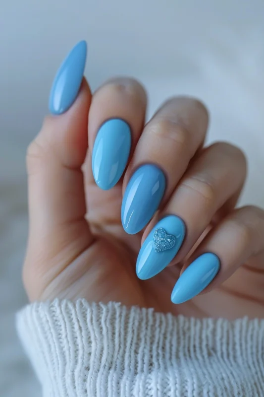 Oval nails with a light blue base and a silver-glittered heart accent.