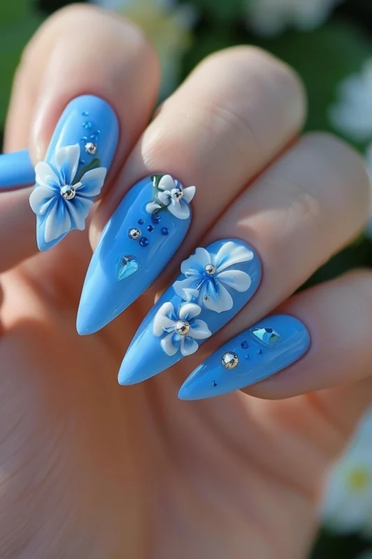 Cobalt blue nails with 3D flowers and rhinestones.