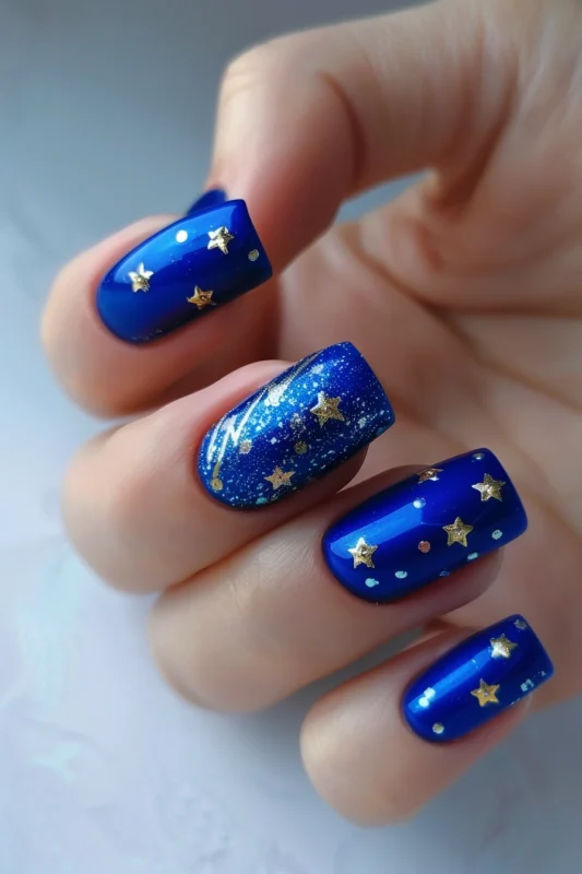 Square blue nails adorned with gold and silver star appliqués.